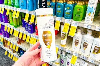 person holding a bottle of pantene shampoo in front of the shampoo shelves