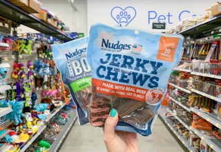 two bags of tyson nudges jerky treats for dogs being held in center of pet care aisle