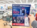 A person holding a black friday ad up in front of a shopping basket.