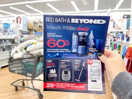 A person holding a black friday ad up in front of a shopping basket.