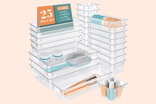 A 25-piece clear drawer organizer tray set is stacked by size. Several cosmetic items are in the trays.