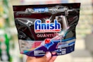 hand holding one pack of Finish Powerball quantum dishwashing tablets in aisle