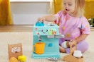 Lifestyle image of a little girl playing with the Fisher-Price Laugh & Learn Learn & Serve Coffee Café playset