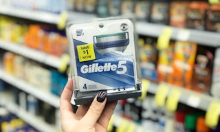 A hand holding a package of Gillette5 razor blade refills.