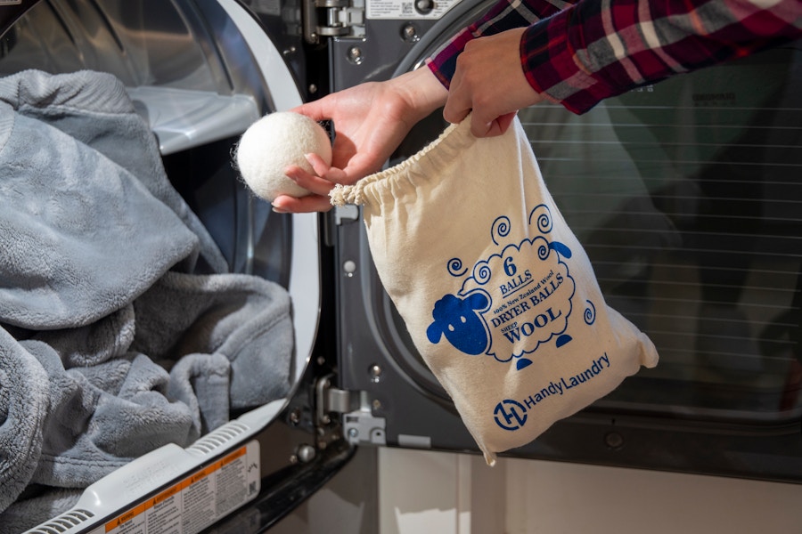 A person throwing wool dryer balls into a dryer.