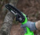 a person sawing a log with a mini chainsaw