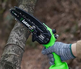 a person sawing a log with a mini chainsaw