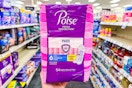 person holding a package of poise pads in an aisle