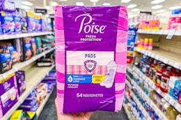 person holding a package of poise pads in an aisle