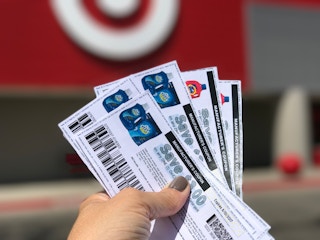 hand holding multiple fanned out coupons with a Target in the background
