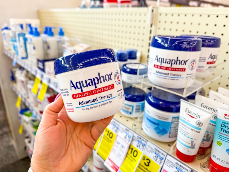person holding a tub of aquaphor by the display