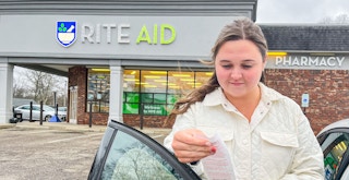 person looking at receipt in front of rite aid sign