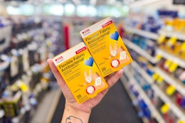 person holding 2 boxes of bandages in an aisle