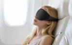 a person sleeping on a plane with a sleep mask on