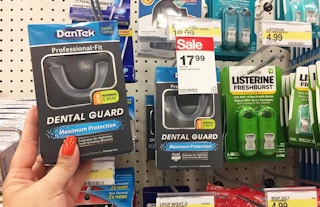 A hand holding a DenTek dental guard in a store aisle