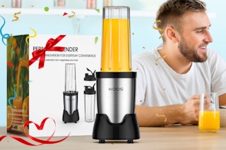 a person blender on a table with it's packaging and a person drinking a smoothie