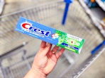 hand holding a box of Crest toothpaste