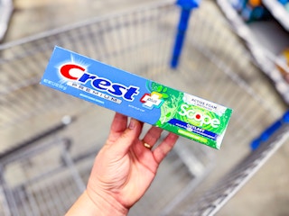 hand holding a box of Crest toothpaste