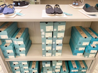 toms shoes on display with shoe boxes below on shelfs