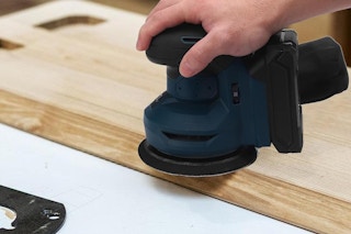 an orbital sander being used on wood