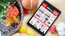 The Office Max Office Depot 2022 Black Friday advertisement displayed on an iPad sitting on a table decorated for autumn.