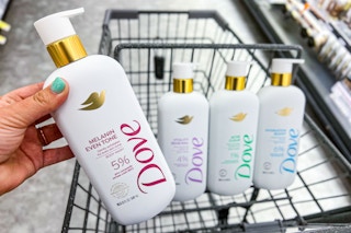 hand holding a bottle of dove serum body wash over in a shopping cart with more bottles