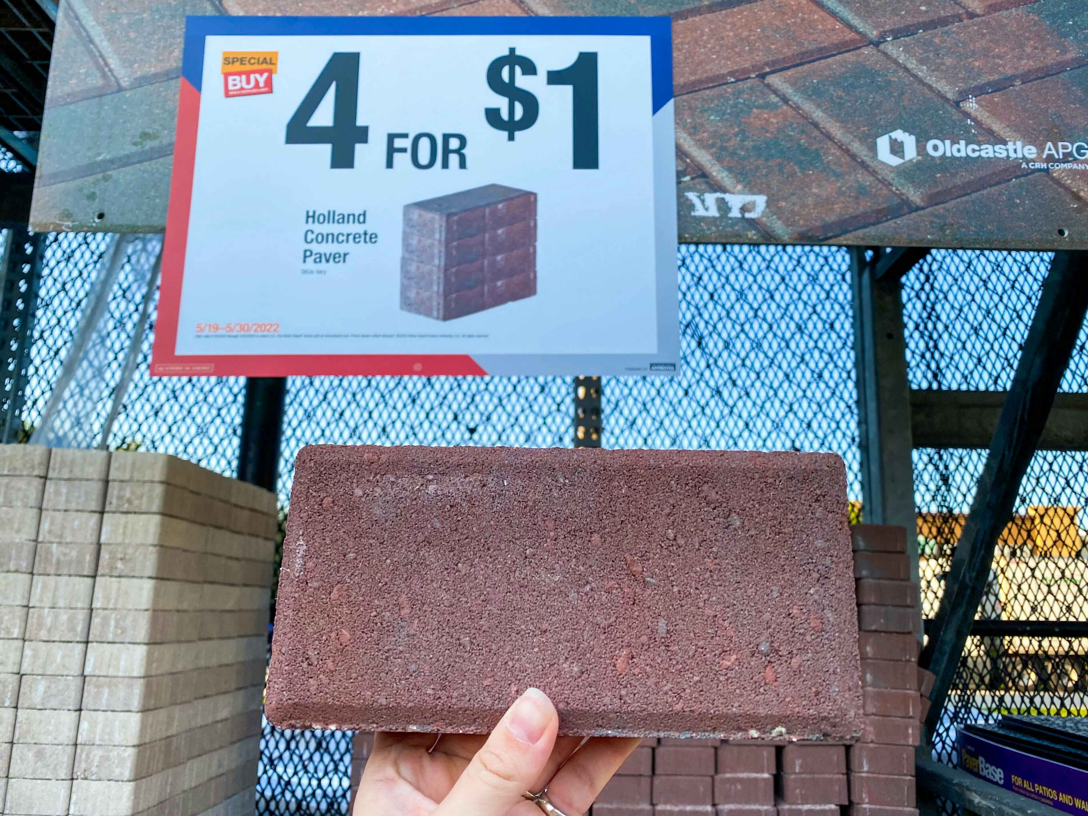 one concrete paver at home depot next to a 4 for $1 concrete pavers sign