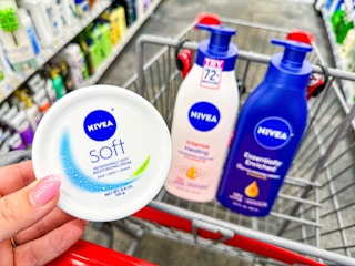 hand holding a Nivea Soft lotion container with two Nivea body lotions in cart behind item