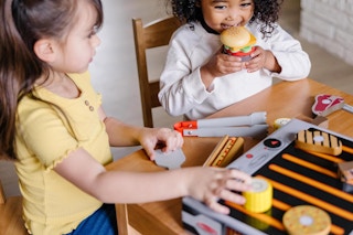 Two little girls play with the Melissa & Doug Barbecue BBQ Grill Set at a table.