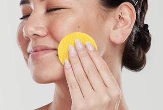 a person using a turmeric cleansing pad on their face