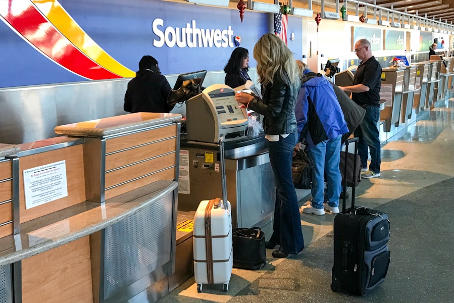 A person standing at the Southwest airlines check in desk at the airport