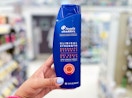 hand holding a bottle of Head and Shoulders Clinical shampoo in aisle