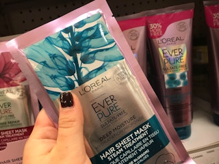 A person's hand holding a L'Oreal sheet mask.