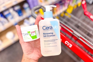 hand holding cerave cleansing balm and facial cleanser above cvs shopping cart