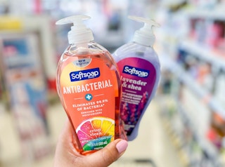 hand holding two bottles of Softsoap hand soap in aisle