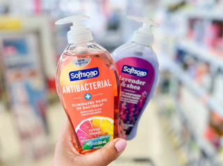 hand holding two bottles of Softsoap hand soap in aisle