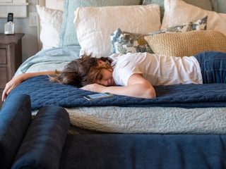 A woman laying on a bed next to her cell phone.