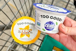 hand putting a cup of two good yogurt in shopping cart
