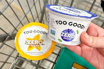hand putting a cup of two good yogurt in shopping cart