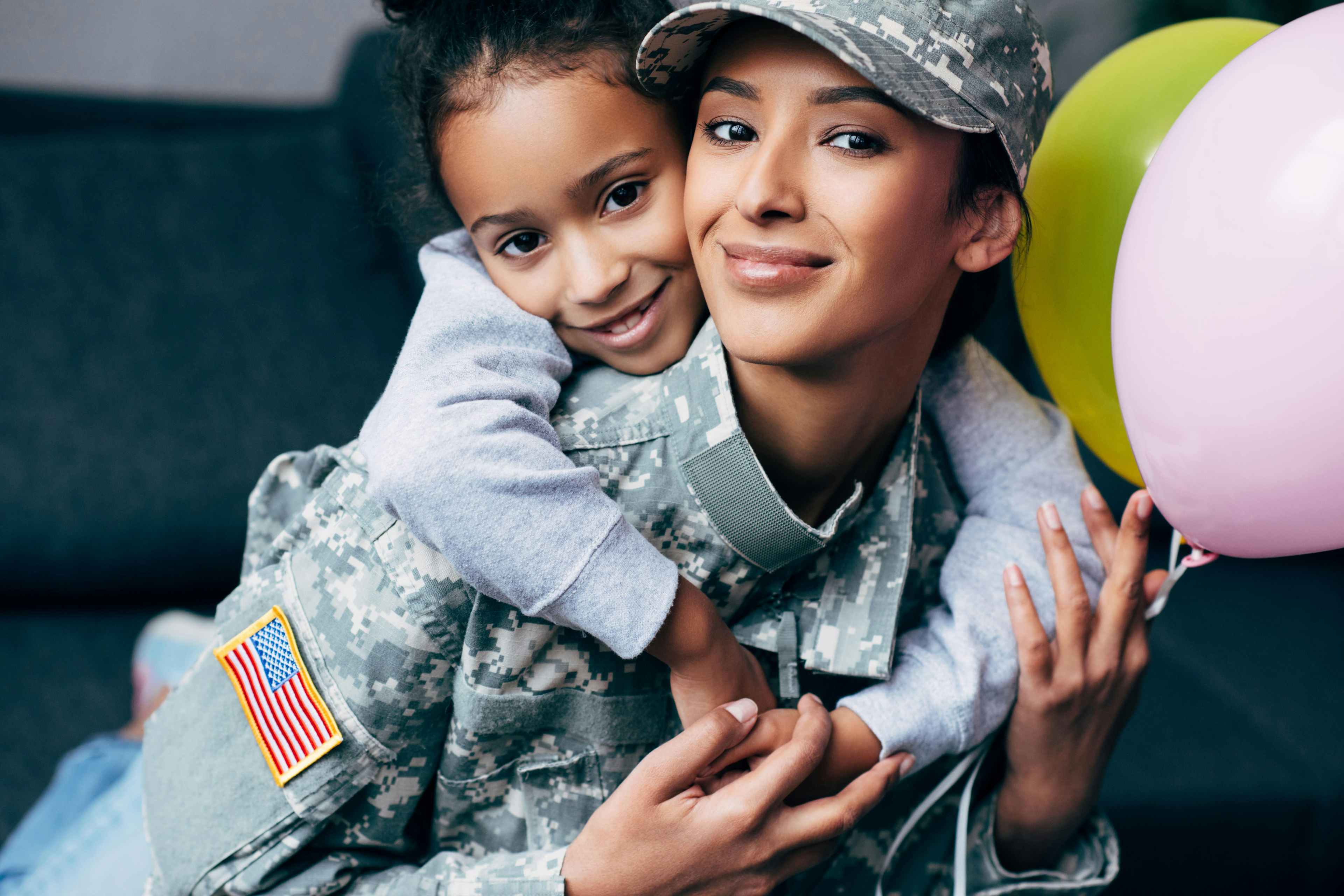 a military mom in uniform getting a hug from her daughter 