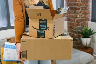 A person carrying some Amazon boxes
