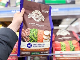 hand holding a bag of supreme source dog food in walmart aisle