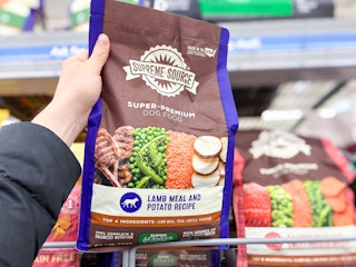 hand holding a bag of supreme source dog food in walmart aisle