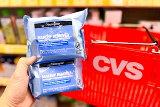 hand holding two packs of neutrogena makeup wipes in front of a CVS shopping basket