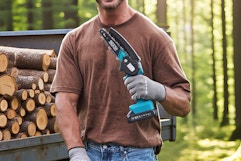 Man holding the Seesii Mini Chainsaw in front of a pile of logs on a truck bed.