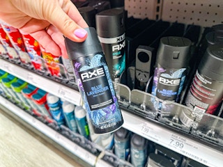 hand holding an axe fine fragrance body spray in front of a shelf