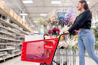 a woman pushing a michaels shopping cart in store