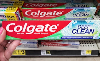 hand holding Colgate toothpaste in front of Dollar General shelf