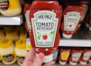 a hand holding a bottle of ketchup 
