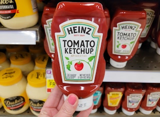 a hand holding a bottle of ketchup